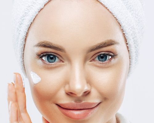 Woman applying cream to her face with a white background